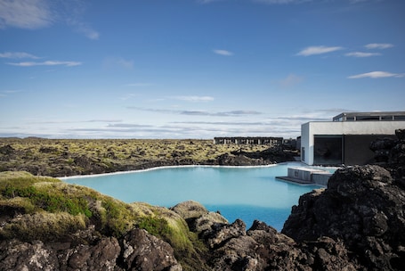 A modern building with a pool surrounded by rocky terrain and sparse vegetation.