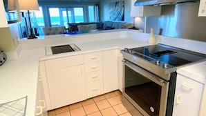 A modern kitchen with white cabinetry, a built-in oven, and a large island with a sink. - Beach Club Villa 29 by Deserving Vacations (Isle of Palms)