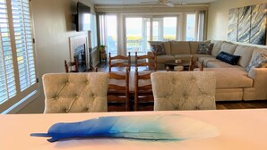 A living room with a fireplace, a sofa, a dining table with chairs, and a ceiling fan. - Beach Club Villa 29 by Deserving Vacations (Isle of Palms)