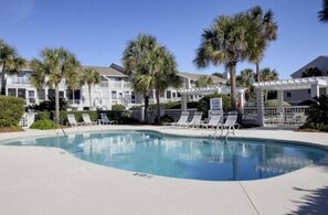 Relax by the resort's large, curved pool surrounded by lounge chairs and palm trees.