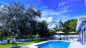 A swimming pool with a hot tub, wooden steps, and outdoor furniture.