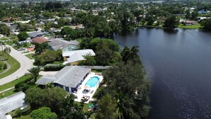 An aerial view of a residential area with houses, a swimming pool, and a lake.