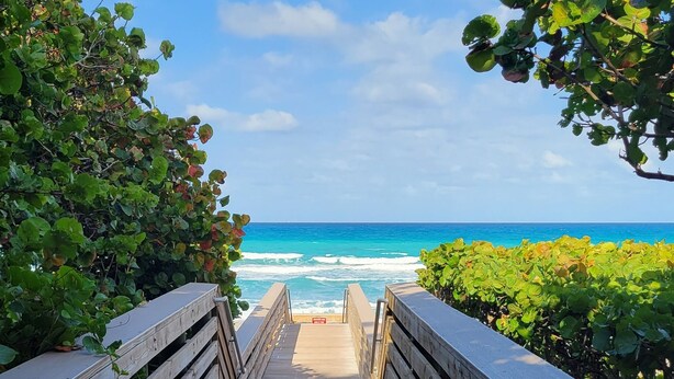 A wooden boardwalk leading to a beach with ocean views.