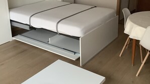 A compact room with a bed, a dining table, and a chair. - Sun-oriented studio Sint-Idesbald with beautiful sea view (Koksijde)