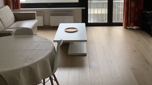 A modern living room with a sofa, a dining table, and a chandelier. - Sun-oriented studio Sint-Idesbald with beautiful sea view (Koksijde)