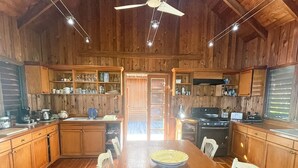 A spacious kitchen with wooden cabinets, a large dining table, and a ceiling fan.