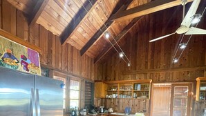 A wooden-paneled kitchen with a stainless steel refrigerator, wooden cabinets, and a wooden dining table.