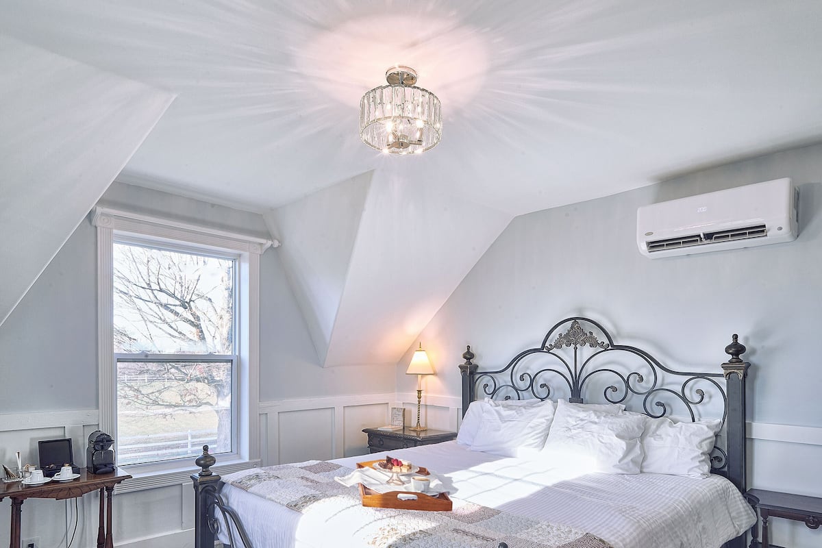 Ein Schlafzimmer mit Bett, Nachttisch, Lampe und einer Deckenleuchte.