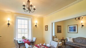 Un coin repas avec une table mise pour le repas, des chaises et un lustre.