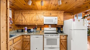 A compact kitchen with wooden cabinets, a microwave, a stove, a dishwasher, and a refrigerator. - Charming & Quiet Mtn-Top Cabin w Grand Panoramic Mountain Views!! DOG Friendly! (Sevierville)