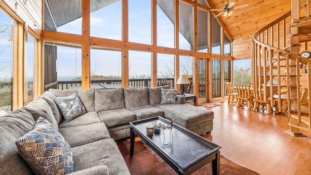 A spacious living room with a large sectional sofa, a coffee table, and wooden chairs. - Charming & Quiet Mtn-Top Cabin w Grand Panoramic Mountain Views!! DOG Friendly! (Sevierville)