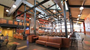 A spacious indoor area with high ceilings, multiple seating arrangements including tables and couches, and a central open space with a staircase. - 4BDRM Games Family Friendly Fire Pit Masthope (Lackawaxen)