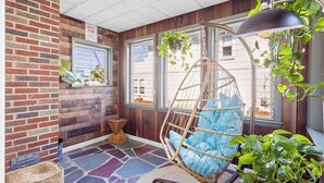 A cozy room with a hanging chair, a brick wall, wooden paneling, and large windows. - Quiet 6BR Family Getaway Near Beach + Casinos (Atlantic City)