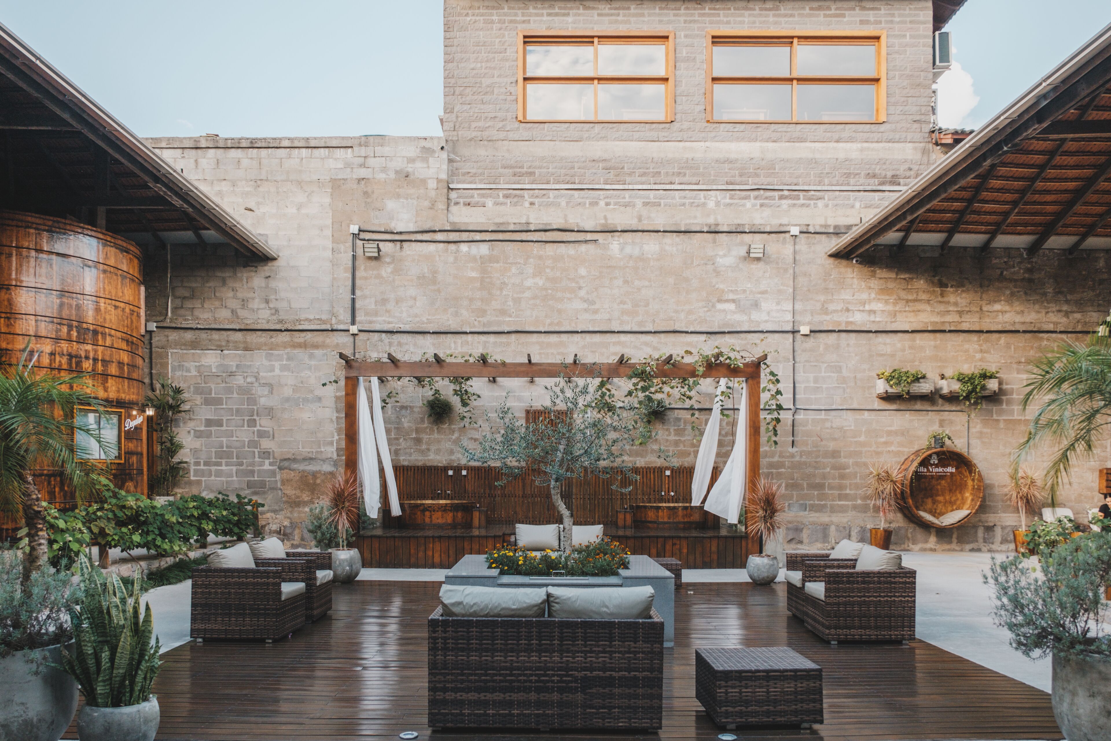 A courtyard with outdoor seating, a brick wall, and a wooden pergola.