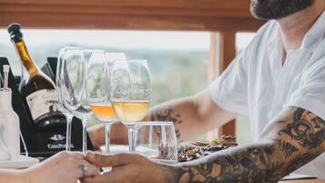 A person with tattoos at a table with wine glasses and a bottle of wine.