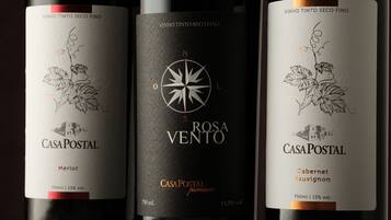 Three wine bottles labeled 'CasaPostal' with different types of wine: Merlot, Rosa Vento, and Cabernet Sauvignon. Each bottle has a unique design and label.