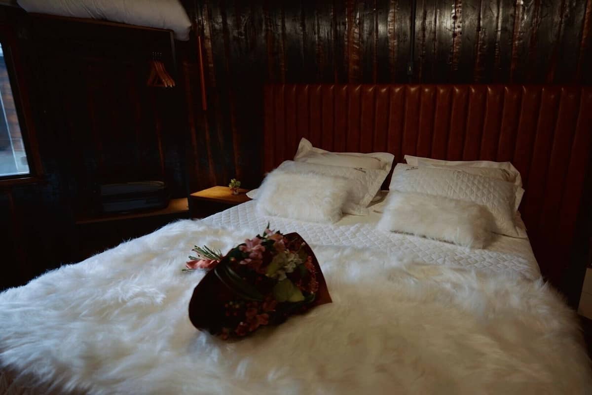 A bed with white bedding, a floral arrangement, and a wooden headboard.