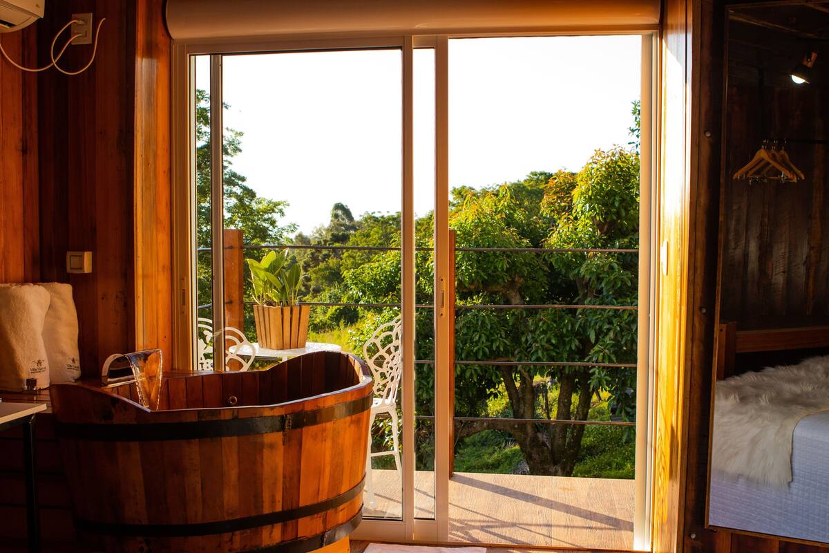 A wooden interior with a large sliding glass door leading to a balcony with a view of greenery.