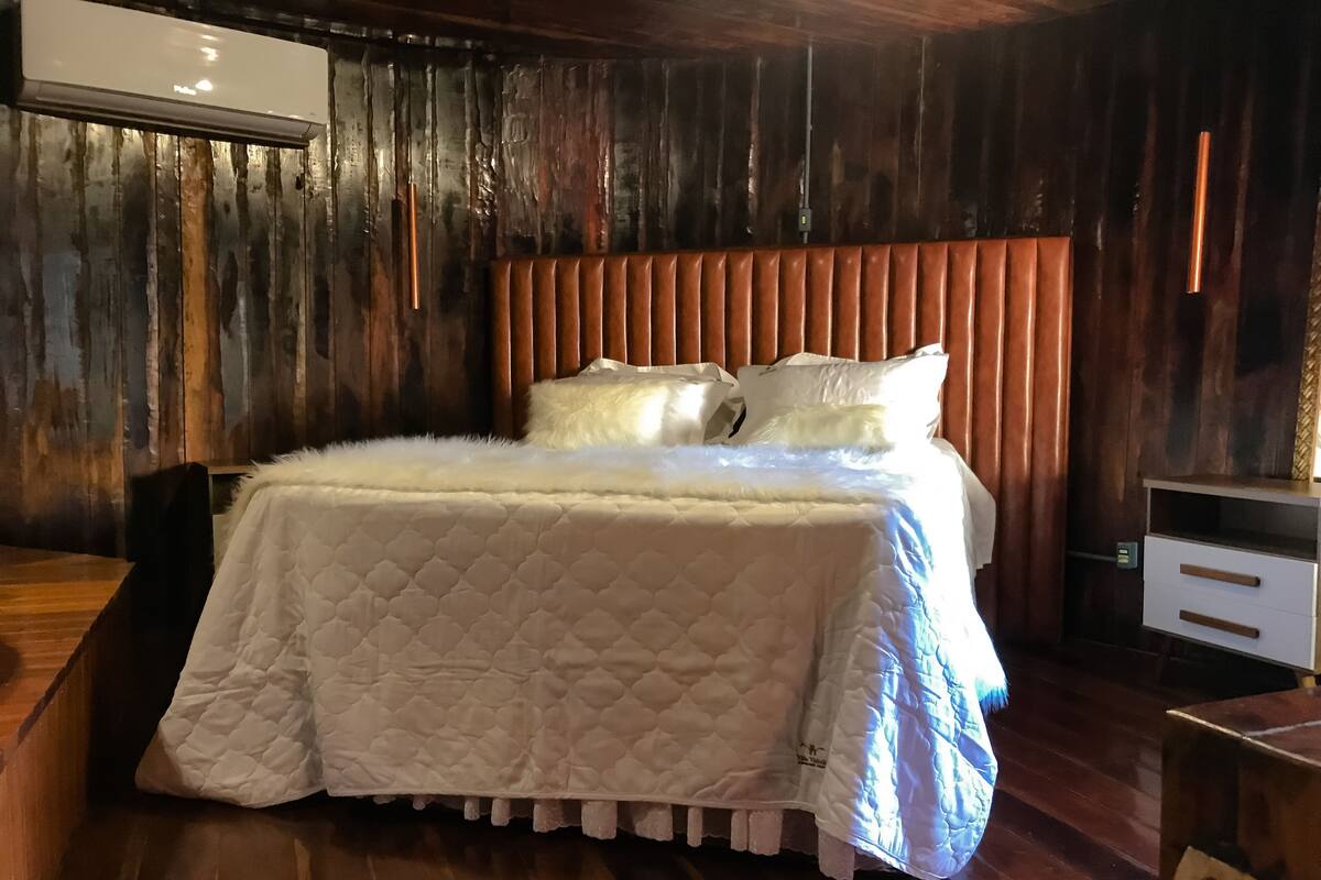 A bed with a white quilted bedspread, a wooden headboard, and white pillows.