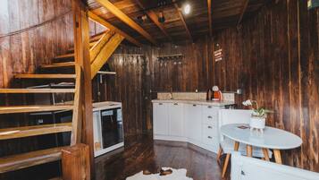 A rustic interior with wooden walls, a white kitchen, and a cowhide rug.