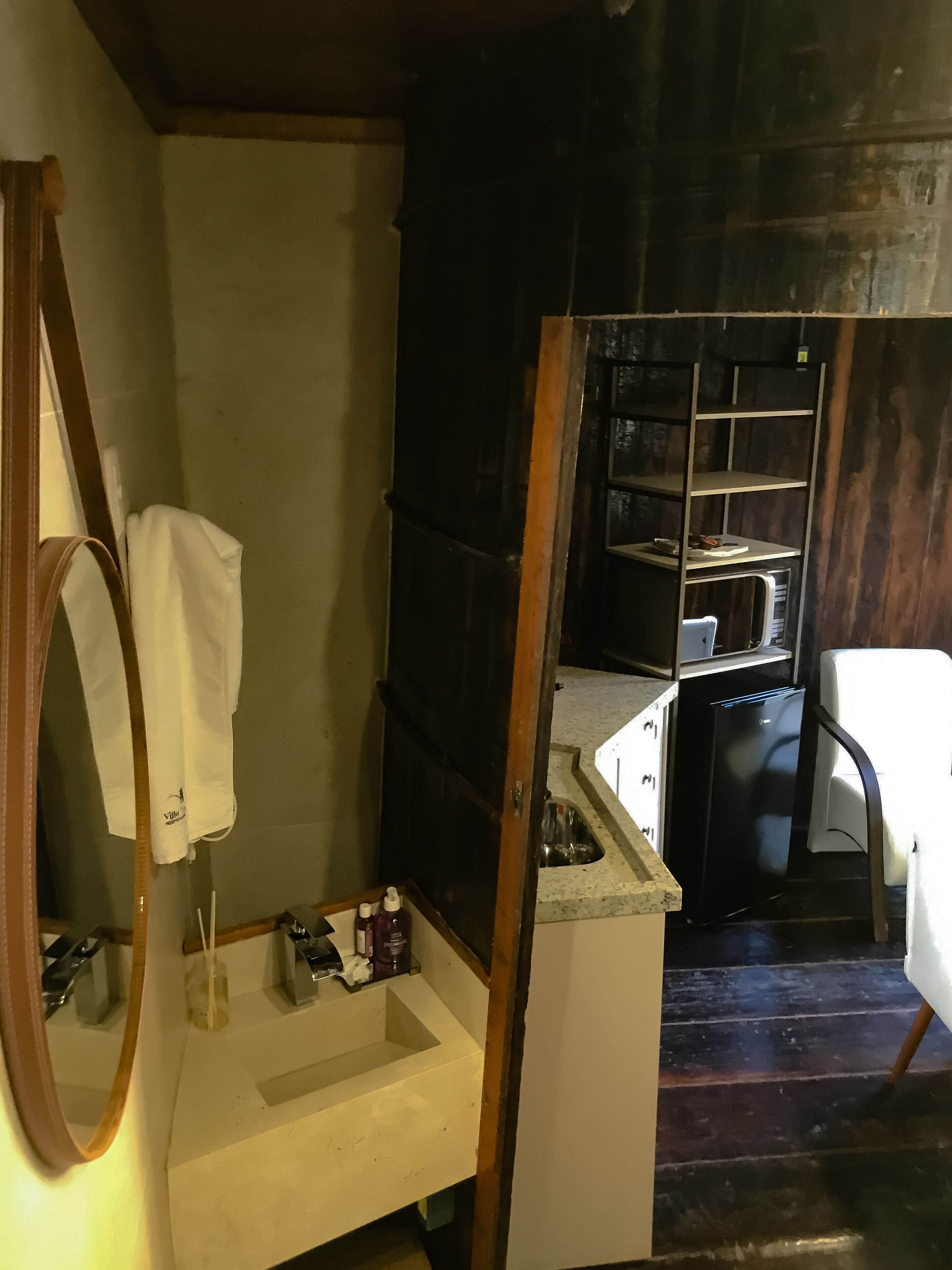 Une petite salle de bain avec un meuble-lavabo en bois, un miroir, un lavabo et une petite étagère contenant des articles de toilette.