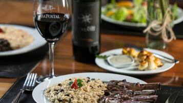 A dining table with plates of food, a wine glass, and a bottle of wine.