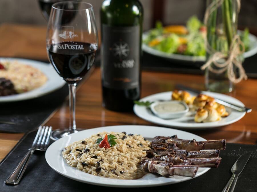 A dining table with plates of food, a wine glass, and a bottle of wine.