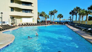 A swimming pool with lounge chairs and palm trees.
