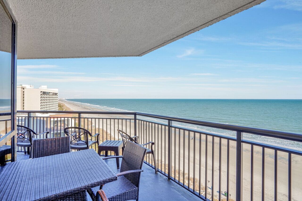 A balcony with a view of the beach and ocean.