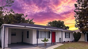 A single-story mobile home with a red front door, a covered porch, and a small front yard. - Most Comfortable Bed • Pet Friendly • 2 Baths • 4 Beds • 4mi to Clearwater Beach (Clearwater)