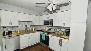A modern kitchen with white cabinets, a microwave, an oven, and a dishwasher. - Most Comfortable Bed • Pet Friendly • 2 Baths • 4 Beds • 4mi to Clearwater Beach (Clearwater)