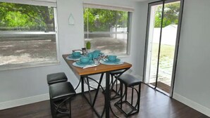 A dining area with a table set for four, large windows, and a view of greenery outside. - Most Comfortable Bed • Pet Friendly • 2 Baths • 4 Beds • 4mi to Clearwater Beach (Clearwater)