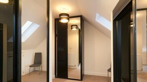 A narrow hallway with a skylight, a chair, and a door leading to another room. - The Terrace (Derby)