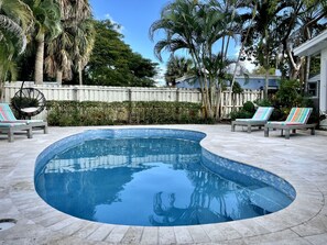 Relax by the serene pool surrounded by lush vegetation and a comfortable deck.