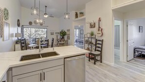 Cocina moderna con encimera de mármol, lavavajillas integrado e iluminación colgante.