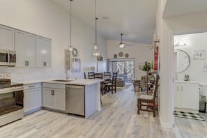 A modern kitchen with white cabinets, a central island, and pendant lighting.
