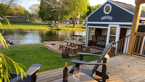 Une terrasse en bois avec des sièges d’extérieur, une bouteille de vin et un verre sur une table.