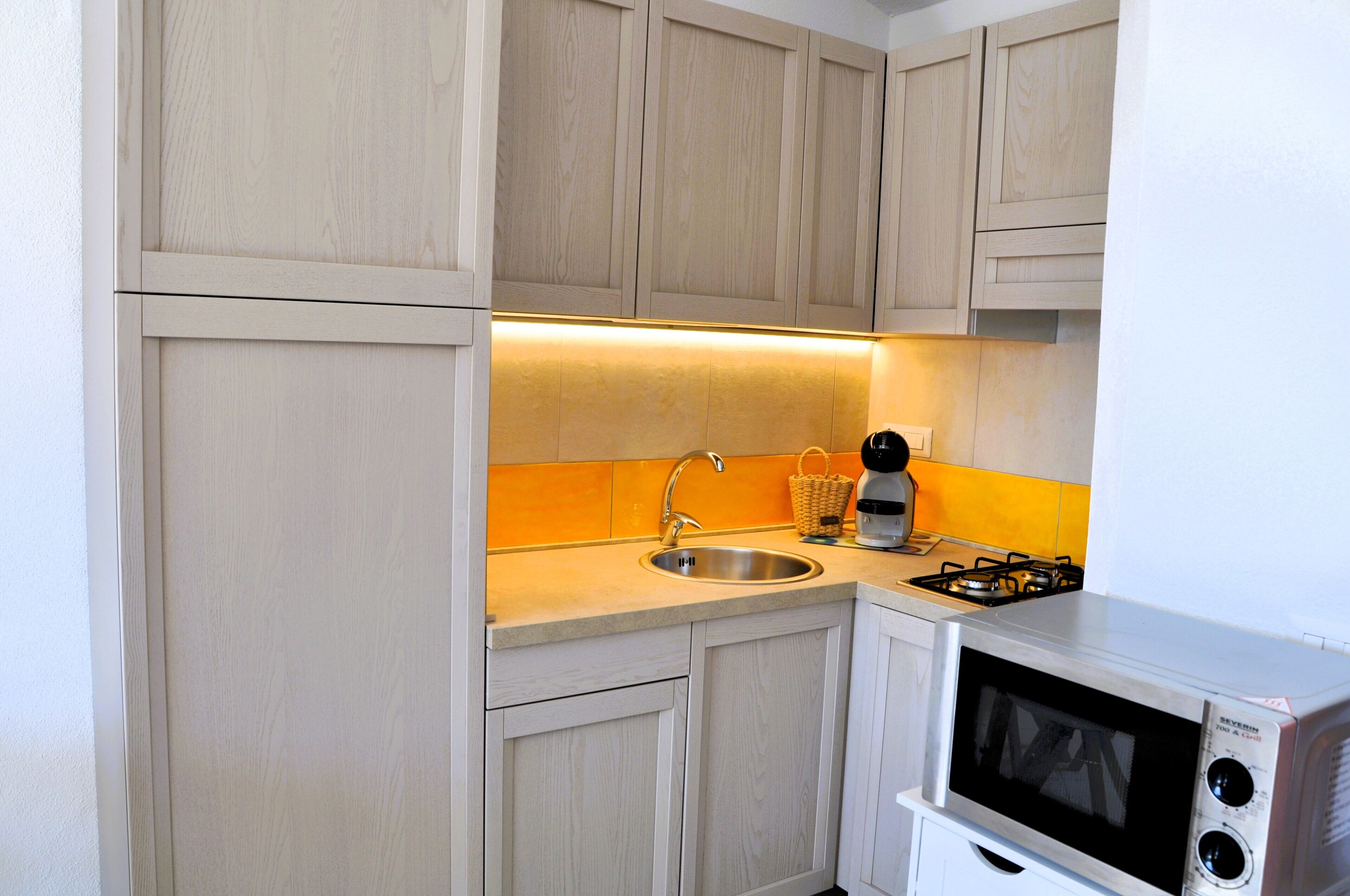 A compact kitchen with a sink, a microwave, and a gas stove.