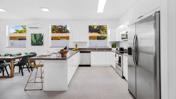 Uma cozinha moderna com armários brancos, eletrodomésticos de aço inoxidável e uma ilha central.