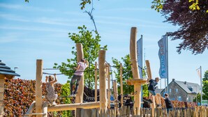 Un parque infantil con estructuras de madera para escalar y un puente colgante.