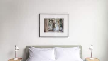 Une chambre à coucher bien rangée, avec un lit, deux tables de chevet et un tableau encadré au mur.