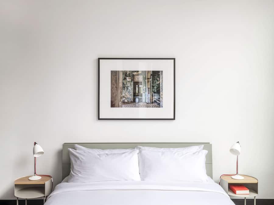 Une chambre à coucher bien rangée, avec un lit, deux tables de chevet et un tableau encadré au mur.