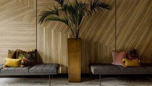 A modern interior with a geometric patterned wall, a tall vase with green plants, and two grey sofas with cushions. - ROOST Cleveland (Cleveland)