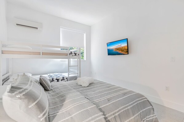 Une chambre avec un lit superposé, une grande fenêtre et un tableau représentant un paysage urbain accroché au mur.
