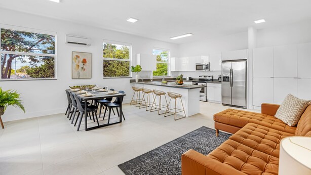 A modern kitchen with white cabinets, a stainless steel refrigerator, and a dining area with a table and chairs. - UP TO 12 GUESTS! Modern house near Wynwood (Miami)