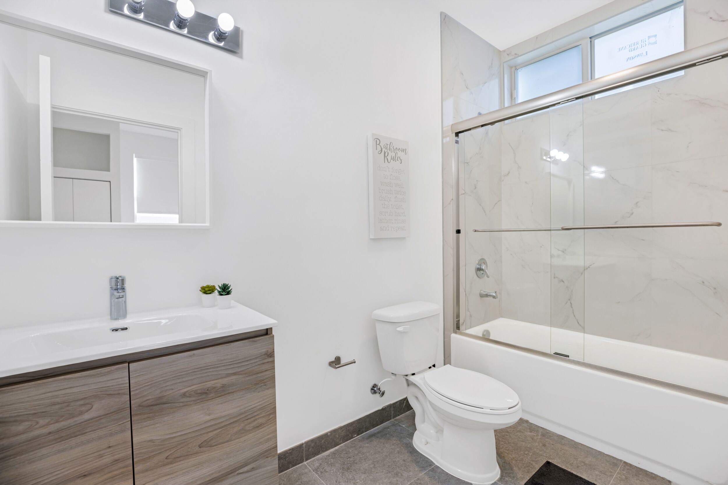 A modern bathroom with a vanity, toilet, and a walk-in shower.