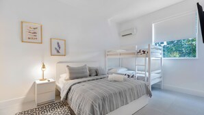 A modern bedroom with a bunk bed, a bedside table with a lamp, and two framed pictures on the wall. - UP TO 12 GUESTS! Modern house near Wynwood (Miami)