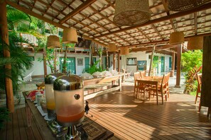 A wooden deck with a bar area, outdoor seating, and lush tropical plants. - Tropical Beach (Porto Seguro)