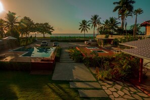 A pool area with a view of the ocean, palm trees, and a paved walkway. - Tropical Beach (Porto Seguro)