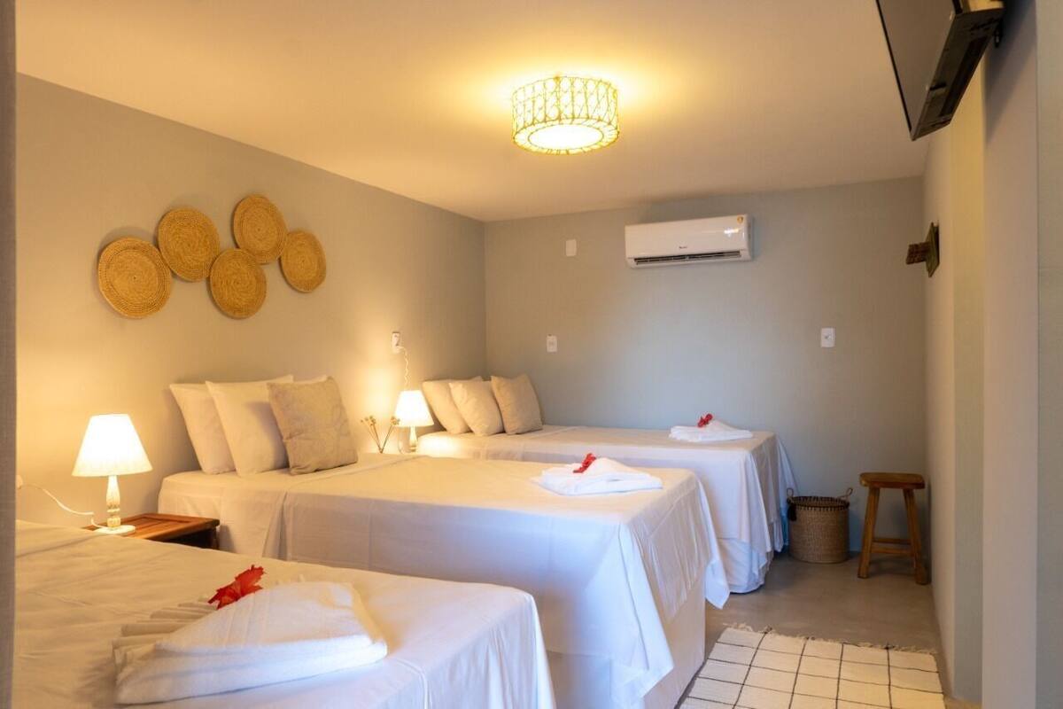 Quarto de hotel com duas camas, uma luminária no teto, ar condicionado e aromatizador de ambiente fixado na parede.